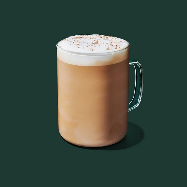A creamy pistachio latte in a Starbucks cup, topped with whipped cream and a sprinkle of delicious nutty crumbs. Try this cozy drink!